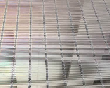 A door curtain made from stainless steel cable mesh has a colorful light in the sunshine