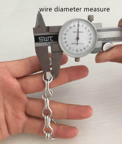 A hand is holding the chain link curtain and the other hand is measuring the wire diameter by vernier caliper.