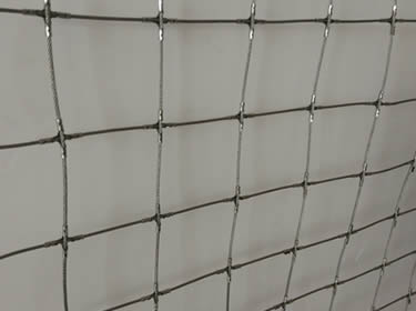 Un morceau de maille de corde carrée avec des pinces cruciales à côté du mur