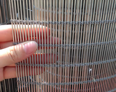 A roll of stainless steel cable mesh and a hand take it
