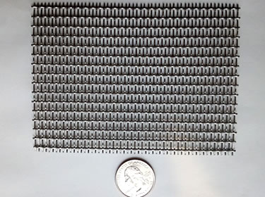 A piece of silver white fine woven mesh is beside a metal coin.