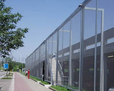 Stainless steel cable mesh fence separates the parking lot and street