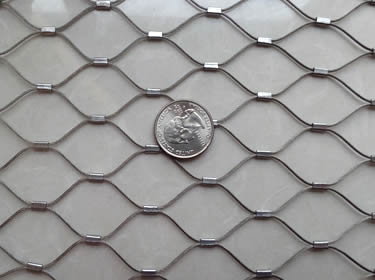 A piece of stainless steel ferrule type rope mesh with a metal coin on it.